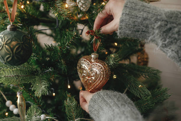 istock Hands decorating christmas tree with stylish bauble in atmospheric festive room. Merry Christmas! Winter holidays preparation. Woman in cozy sweater putting vintage toy on tree 1434114372