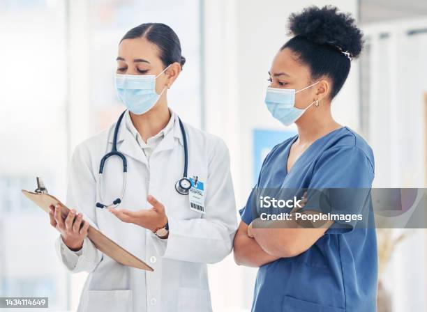 Doctor And Nurse Reading Medical Information Paperwork With Mask For Safety From Covid Or Corona Virus In A Hospital Healthcare Workers Discuss And Analyze Pandemic Data Report In A Clinic Together Stock Photo - Download Image Now