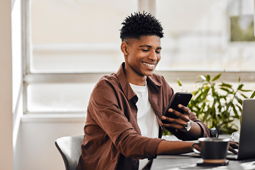 Coffee, phone, and black man networking on social media searching for online content on news app. Smile, communication and happy student texting and typing a sms or browsing the internet at a cafe