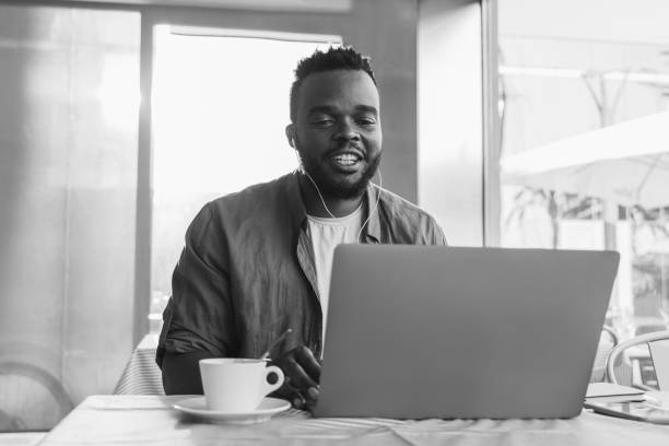 istock Young African student doing online meeting video class at university cafeteria - Focus on face - Black and white editing 1434114861