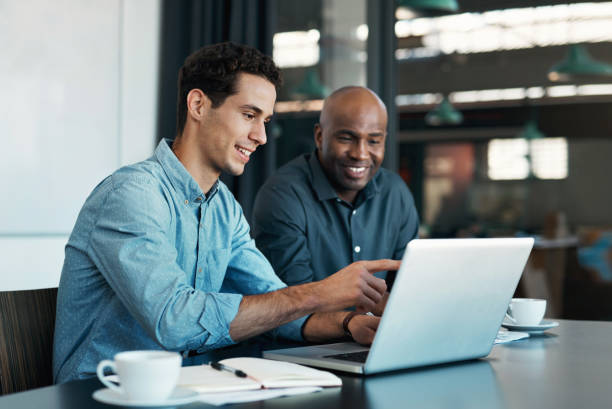 trabajo en equipo, diversidad y gerente de ventas planificando ideas de marca con un diseñador creativo en una computadora portátil en una oficina. logotipo, colaboración y empresario hablando con un empleado sobre un proyecto de desarrollo - empleada administrativa fotografías e imágenes de stock