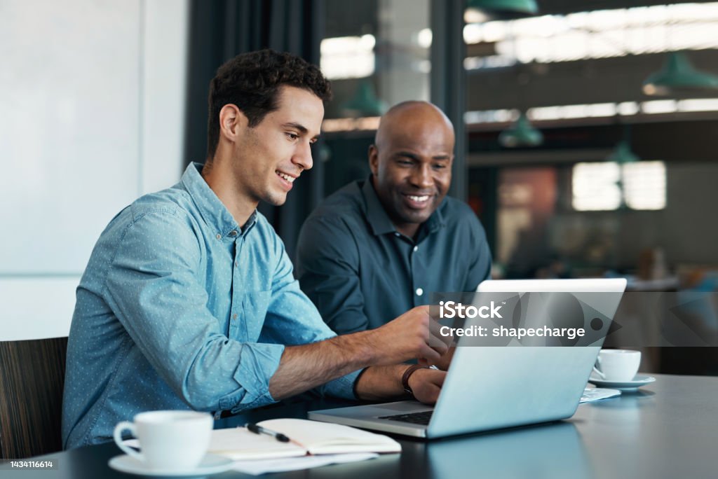 Teamwork, diversity and sales manager planning branding ideas with a creative designer on a laptop in an office. Logo, collaboration and businessman talking to an employee about a development project Computer Stock Photo