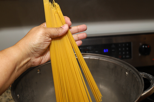 A black woman cooking spaghetti