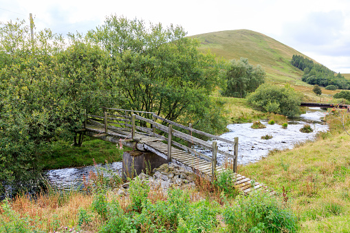 Old rickety wooden foot bridge over Megget water in the Scottish Borders