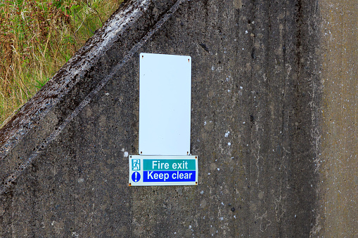 Fire exit and keep clear sign fixed to concrete wall