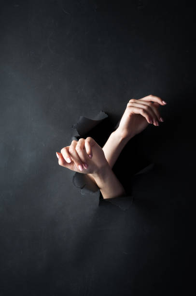 istock Female hands, on a black, torn background. 1434118824