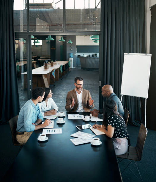 Team diversity, business and meeting at table to have conversation for group project, planning or strategy for startup company in office. Brainstorming, teamwork and communicate finance in workspace stock photo