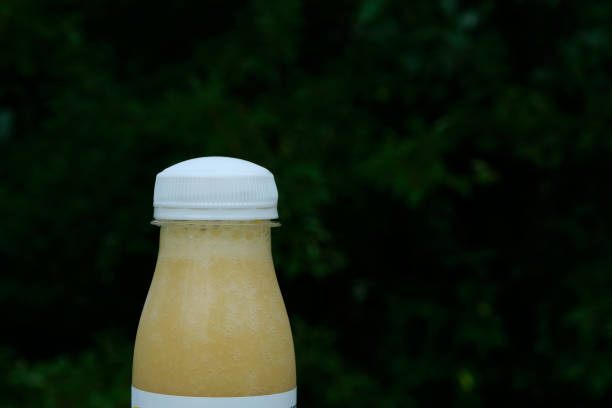 Swollen bloated packaging fruit smoothie with dangerous bacteria microbes, close-up. Pathogenic bacteria and fungi in natural drinks.