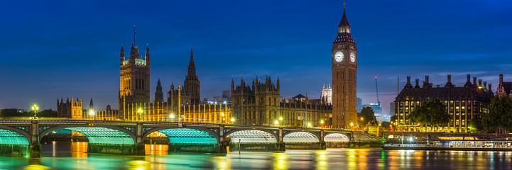 Panoramic night time view across the River Thames past the Westminster Bridge to Big Ben and the Houses of Parliament in the heart of London, UK.