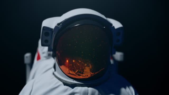 Astronaut in a space helmet turning from left to right, facing camera in the middle