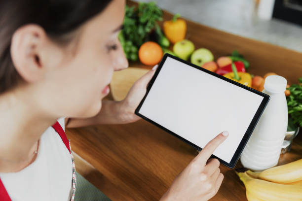 Kitchen. Young woman using phone, girl hands holding tablet with empty screen