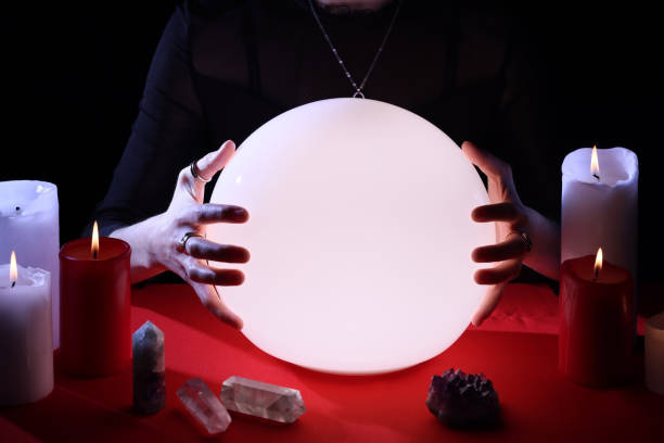 istock Soothsayer using glowing crystal ball to predict future  at table in darkness, closeup. Fortune telling 1434132401