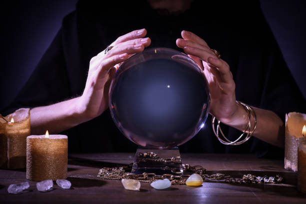 istock Soothsayer using crystal ball to predict future at table in darkness, closeup. Fortune telling 1434132429