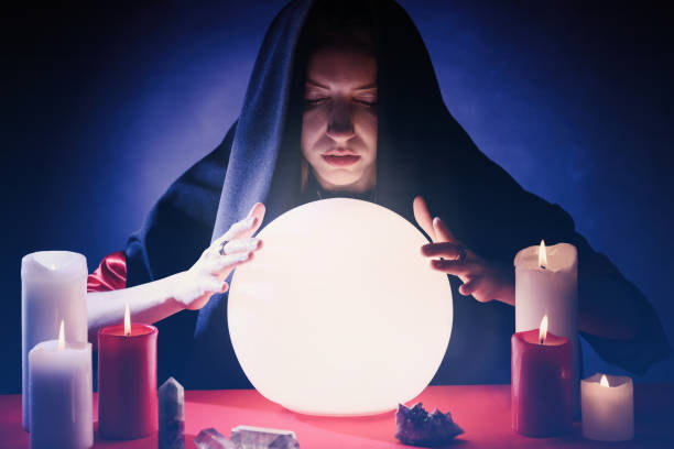 istock Soothsayer using glowing crystal ball to predict future at table in darkness. Fortune telling 1434132496