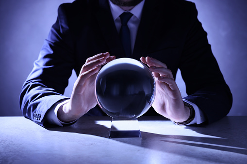 Businessman using crystal ball to predict future at table, closeup
