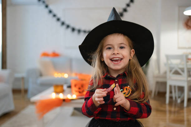 Toddler girl, dressed as a witch for a Halloween, eating gummy bears stock photo