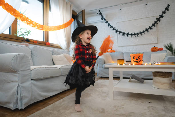 dziewczynka przebrana za czarownicę biegnąca z miotłą, podczas halloween - house halloween autumn candid zdjęcia i obrazy z banku zdjęć