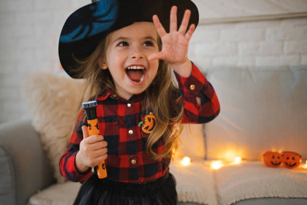 istock Caucasian toddler girl, dressed as a witch for a Halloween, playing with flashlight 1434133082