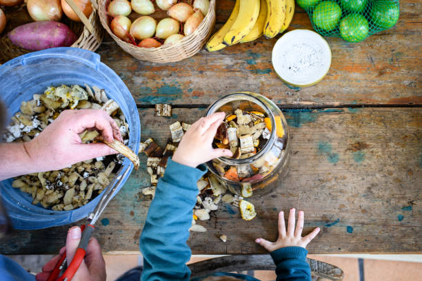 Father and son working together on preparing compost in a glass jar at home. A joint family work for sustainability, avoiding the generation of waste in large cities and promoting organic fertilization in home gardens. Já