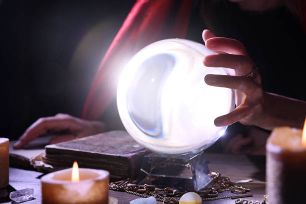 istock Soothsayer using crystal ball to predict future at table in darkness, closeup. Fortune telling 1434136441