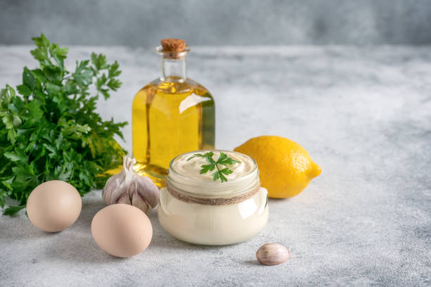 istock Aioli sauce with ingredients on a light gray grunge background. Side view, selective focus, copy space. 1434136914