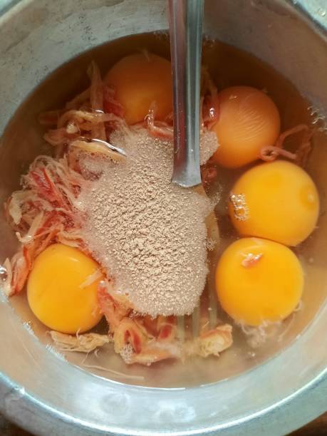 Adding Pepper powder into bowl of Eggs with shredded squid - food preparation.