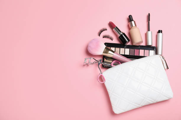 istock Cosmetic bag and makeup products with accessories on pink background, flat lay. Space for text 1434137073