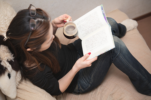 Woman reading a book while drinking coffee