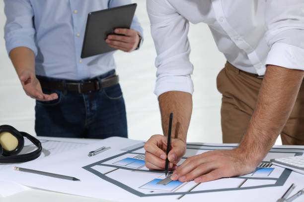istock Architects working with construction drawings at table in office, closeup 1434138791