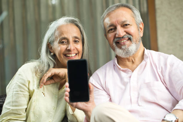 istock Cheerful old couple showing mobile phone screen 1434139111