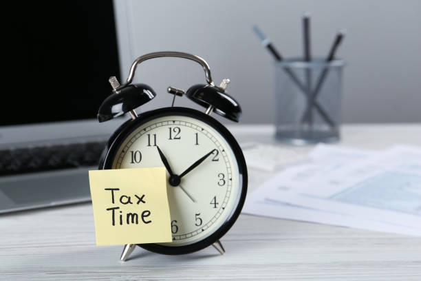 istock Alarm clock and reminder note with words Tax Time on white wooden table. Space for text 1434139720