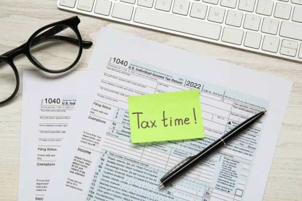istock Reminder note with words Tax Time, documents, keyboard, glasses and pen on white wooden table, flat lay 1434140625