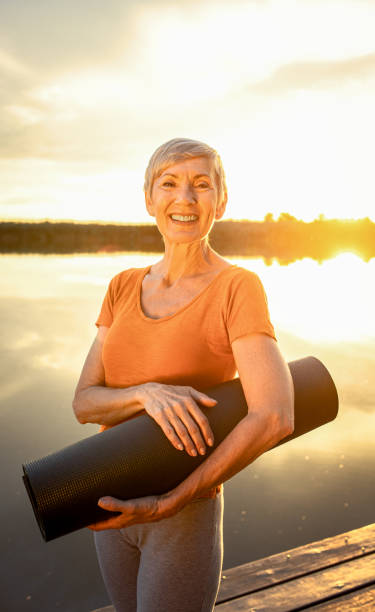portrait of senior woman with yoga mats. - yoga meditating women exercise mat imagens e fotografias de stock