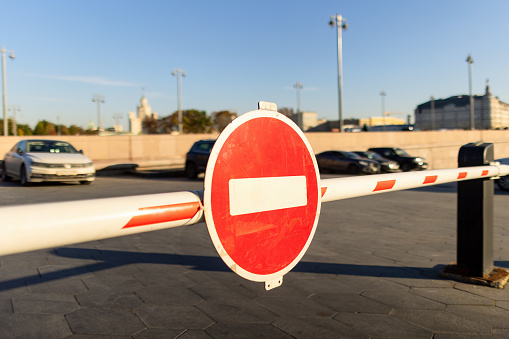 Red round stop sign on an entrance gate on a parking lot