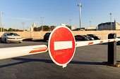 Red round stop sign on an entrance gate on a parking lot