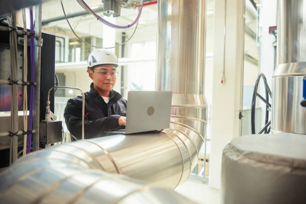 istock Engineer with a laptop working by pipes in a power station 1434144992
