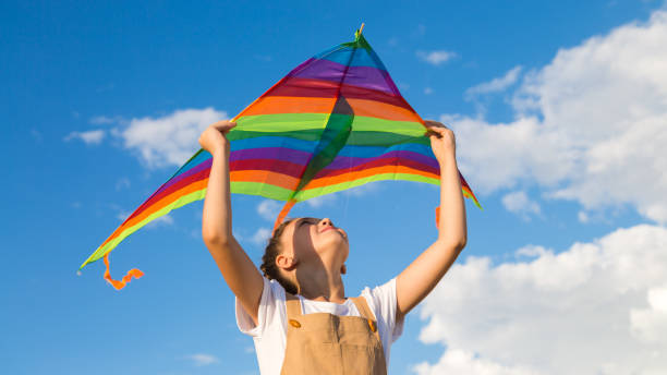 istock The girl alone launches a multicolored kite into the sky 1434145189