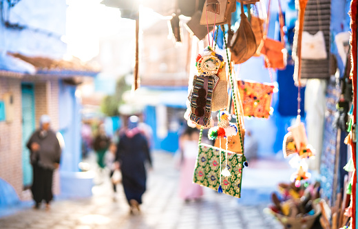 Handcraft textile bags and souvenirs at street market along Chefchaouen streets in Morocco - Travel shopping concept with manufactured handmade objects - Bright vivid filter on blurred background