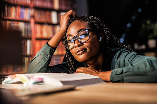 Black female student studying in a library, working late.