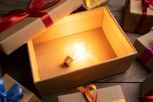 Gift box with light bulb inside on wooden table. Present idea concept. This file is cleaned and retouched.