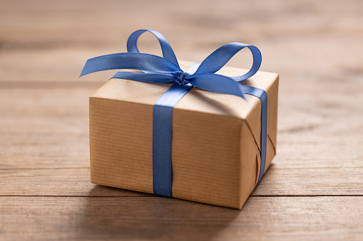 Gift box with blue ribbon on wooden table. This file is cleaned and retouched.