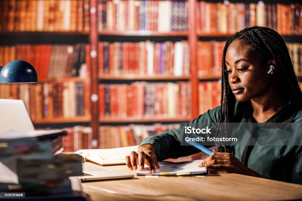 Young student highlight notes while studying in a library Young student highlight notes while studying in a library. African Ethnicity Stock Photo