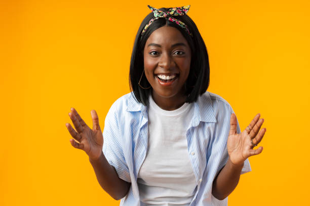 überraschte glückliche junge afrikanerin drückt schock vor gelbem hintergrund aus - female color image human head studio shot stock-fotos und bilder