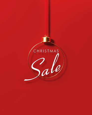 Christmas sale behind gold colored bauble on red background. Christmas and festivity concept. Horizontal composition with copy space.