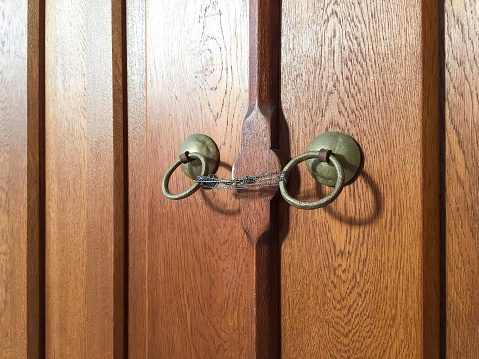 The hand opens the door peephole cover in the front door of light oak.