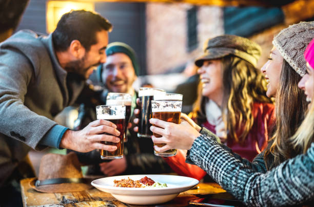 ビール醸造所のバーでビールを飲む幸せな人々 -野外レストランパティオで一緒に冬の時間を楽しむ男女の飲料ライフスタイルコンセプト -グラスに焦点を当てた暖かいフィルター - drinking beer pub bar ストックフォトと画像