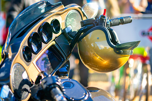 Hamburg, Germany 16. October 2022: Golden jet helmet shines in the sun, attached to the handlebars of an american motorcycle, parked somewhere in hamburg - germany