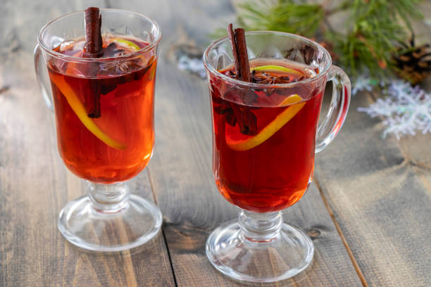 soft focus on two glasses of hot spicy punch with cinnamon sticks, star anise and orange slice on wooden table stock photo