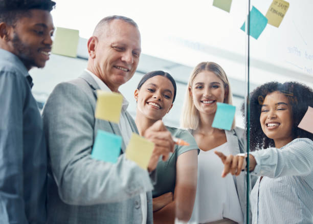 istock Innovation, planning and team collaboration with business people writing schedule and plan on sticky notes. Corporate office employee group happy, excited about creative vision and mission strategy 1434165359