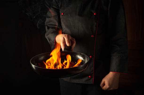 istock Professional chef cooking food in pan with fire flame on black background. Restaurant and hotel service concept. European cuisine. Vegetarian cuisine. 1434165379